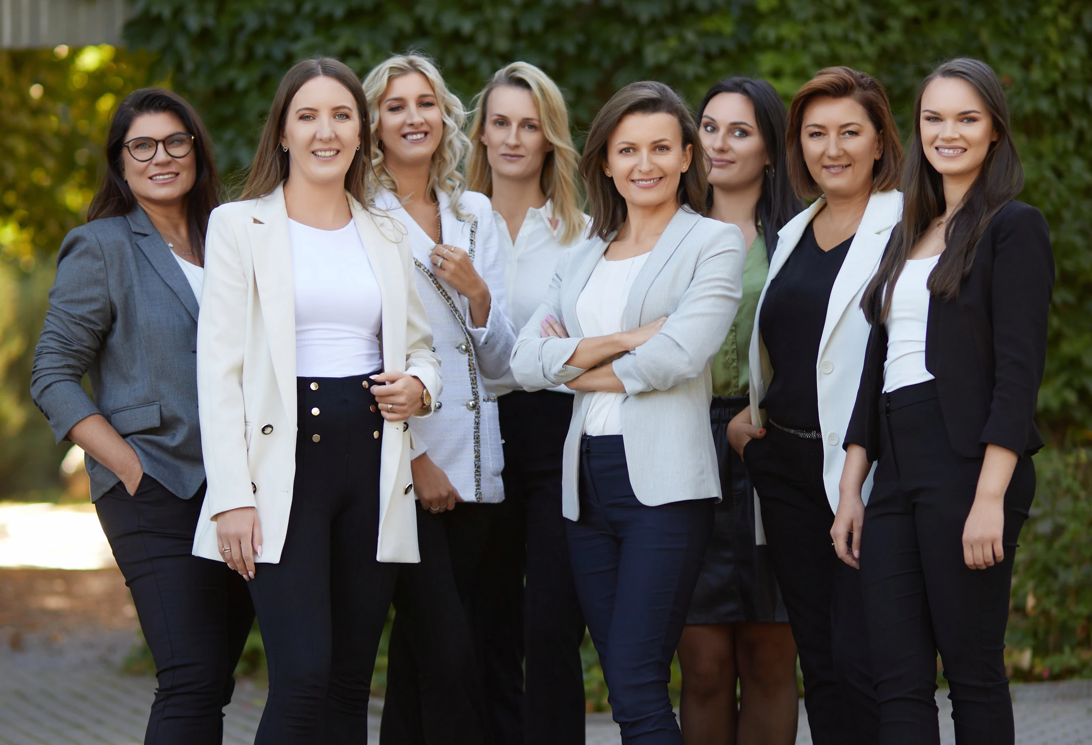 Eight BDG colleagues standing together outdoors in front of greenery