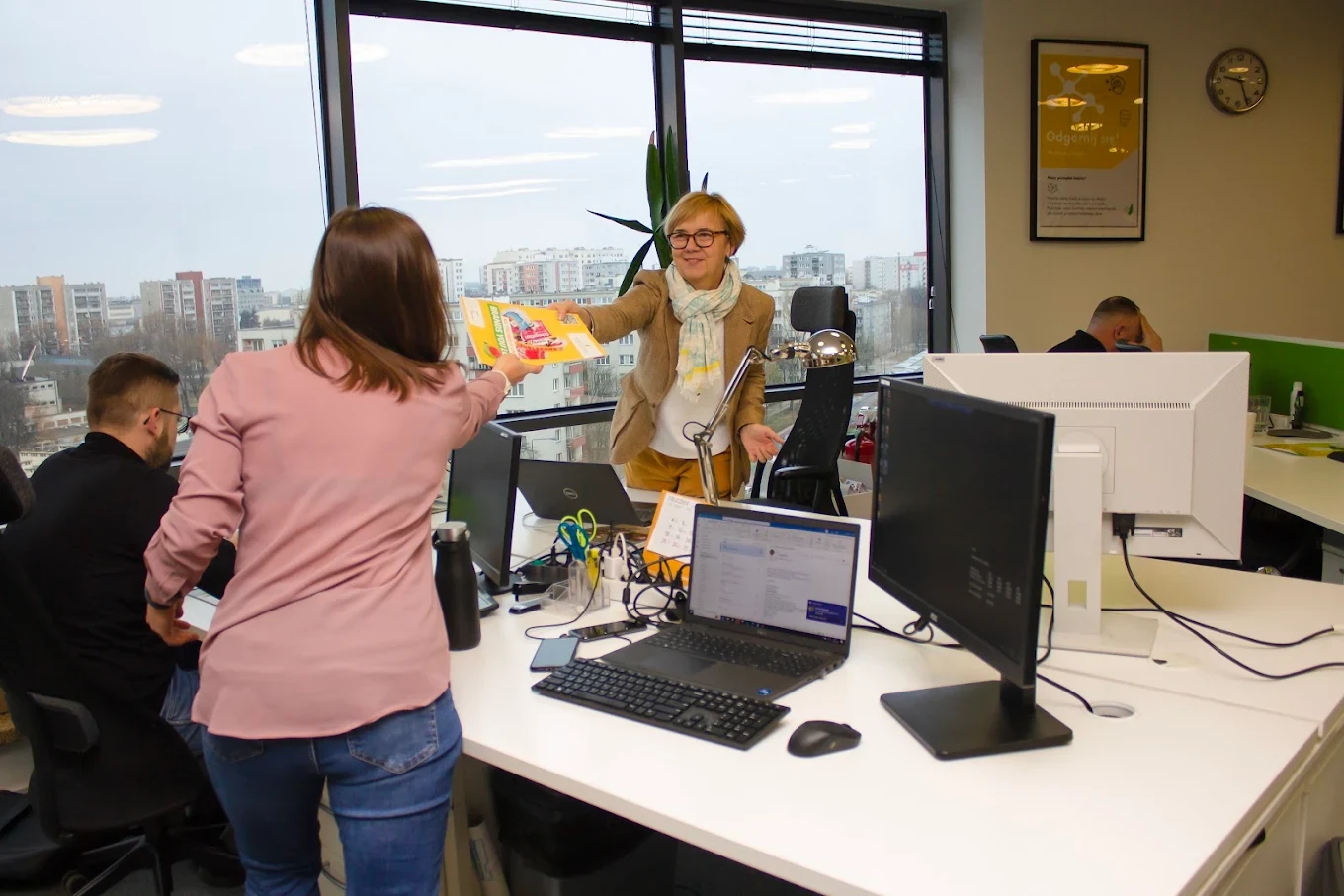 A colleague hands a product leaflet across the desk in the Warsaw office